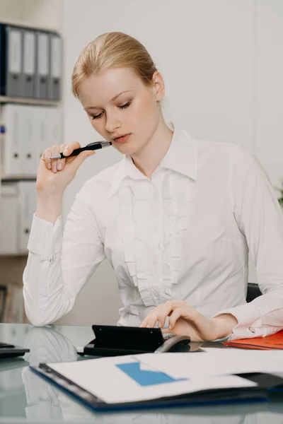 Красива жінка в офісі обчислює свої фінанси на калькуляторі — стокове фото