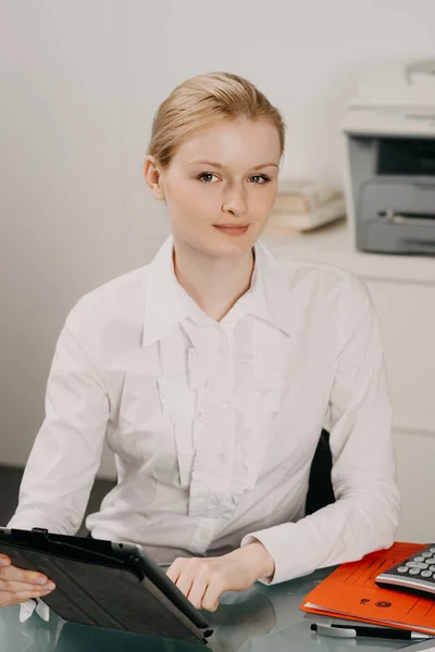 Aantrekkelijke jonge vrouw werkt op tablet in kantoor — Stockfoto