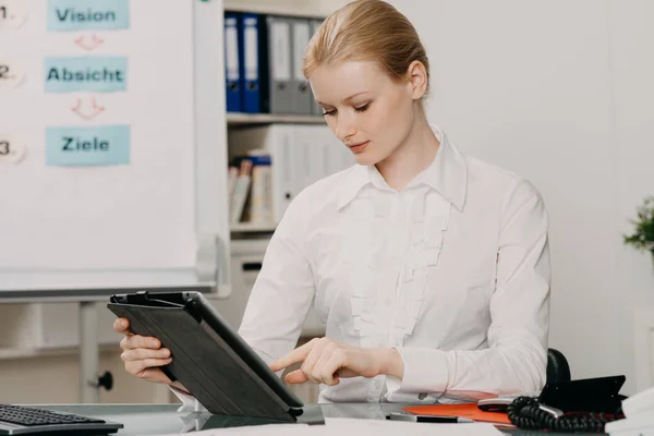 Jovem atraente trabalha em tablet no escritório — Fotografia de Stock