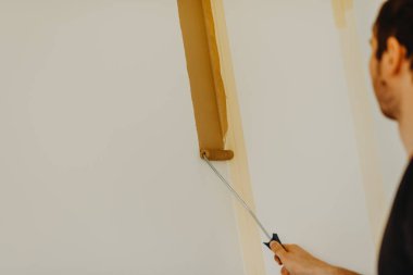 bir rulo ile genç adam boyama duvar eller yukarı kapatın 