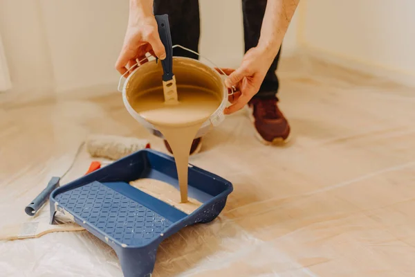 Cerca de las manos vertiendo pintura en una bandeja de pintura — Foto de Stock