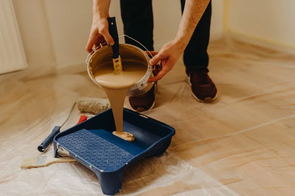 Cerca de las manos vertiendo pintura en una bandeja de pintura — Foto de Stock