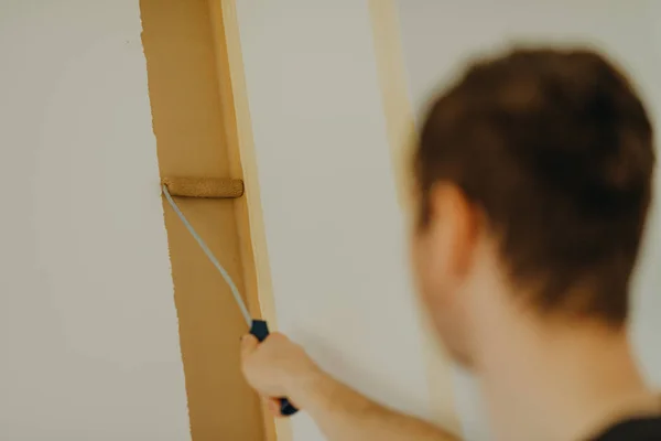 Закрыть руки молодому человеку, рисовавшему стену роликом — стоковое фото