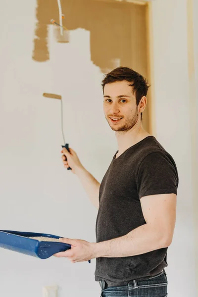 young man painting wall with a roller