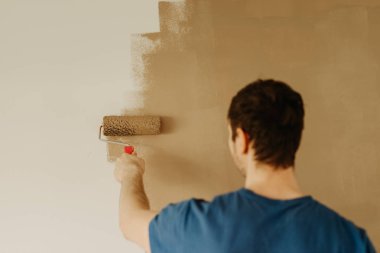 bir rulo ile genç adam boyama duvar eller yukarı kapatın 