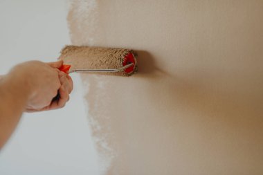 bir rulo ile genç adam boyama duvar eller yukarı kapatın 
