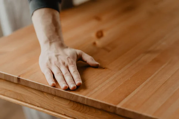 Mann reicht seine Hand über den fertigen Holztisch — Stockfoto