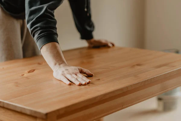 Мужчина протягивает руку над готовым деревянным столом — стоковое фото