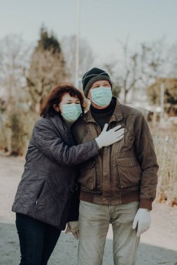 Enfeksiyon tehlikesi sırasında dışarıda yürüyen maskeli ve eldivenli iki yaşlı adam.