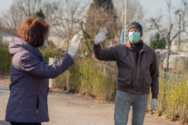 Yüz maskesi ve eldiven takan iki son sınıf öğrencisi. Randevu sırasında dışarıda sallanıyorlar.