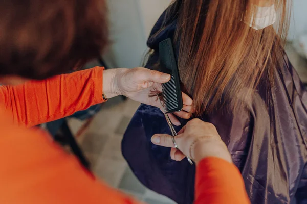 Reife Frau Schneidet Jungen Frau Mit Langen Haaren Hause Haare lizenzfreie Stockbilder