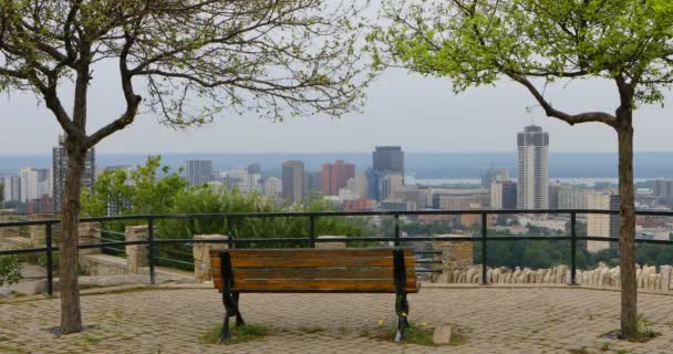 4K UltraHD Hamilton, Canadá skyline con banco de parque en primer plano — Vídeo de stock