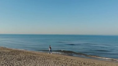 Gün batımında kumsalda koşan genç çift yaz tatilinde eğlenen iki aşığın havadan görüntüsü aşk ve seyahat kavramı.