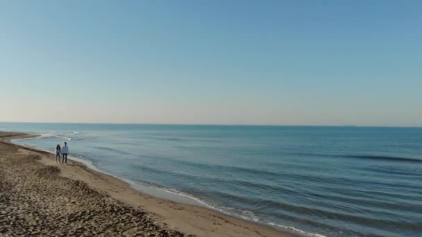 フィウミチーノ イタリア 海のそばを歩いている若いカップル 日の出の男と女は波を背景に海のそばを歩く 空中風景 — ストック動画