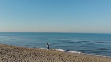 Gün batımında kumsalda koşan genç çift yaz tatilinde eğlenen iki aşığın havadan görüntüsü aşk ve seyahat kavramı.