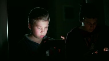 Karanlık bir odada akıllı telefonuyla oyun oynayan iki genç çocuk. karşı akım