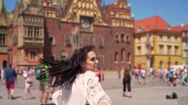 Genç kız eski kasabanın merkez meydanında dönüyor. Turist, yaz gününün tadını çıkarıyor. Turist caddelerinde yürüyor.