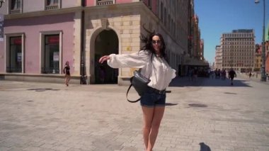 Genç kız eski kasabanın merkez meydanında dönüyor. Turist, yaz gününün tadını çıkarıyor. Turist caddelerinde yürüyor.