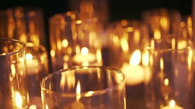 Kapatın. Cam bir şişedeki mum romantik bir atmosferde gece veya akşam düğün töreninde. Mum yakıyorum. Büyük mumlar cam şişelerde yanar. Salon. Romantik bir akşam.