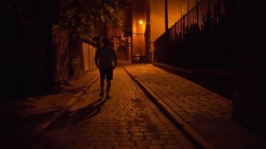 Siluet. Gece yarısı bir adam dar caddede yürür. Karanlık şehir. Biri Karanlık Şehir 'e gider. Eski kasaba mimarisi