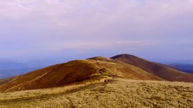 Bir dağ sırasındaki tarla yolu. Kel Dağlar Tepesi 'nin manzarası. Dağ yolunda uçuyor. ATV ya da SUV için bir yol. Doğayla iç içe bir yolculuk. Kuru otlarla kaplı. Hava görünümü