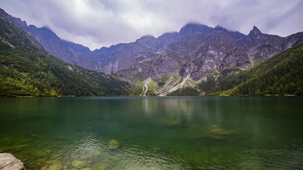 暗い雲と湖の反射と緑の森に覆われた霧の山の景色 ストーニー ショア モースキー 高タトラ ザコパネ ポーランド自然と観光の概念 ストック画像