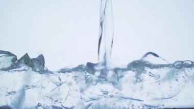 Bardakta buzlu ve köpüklü soda dolduruyorum. Ağır çekimde yakın çekim. Şeffaf mavi arka planda ferahlatıcı, taze maden suyu. Makro. Buz küpleri. Buz ve votka. Tekila cini. tonik