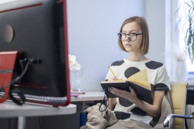 Üniversitede ya da üniversitede uzaktan öğrenim gören bir kız öğrenci. Uzaktan bilim. Evde bir internet sitesi için webinar öğretiyor. Bir özet ya da not defterindeki notlar. Telefon tableti. karantina sırasında