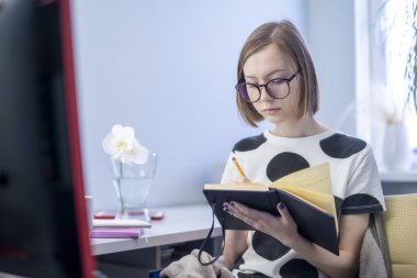 Üniversitede ya da üniversitede uzaktan öğrenim gören bir kız öğrenci. Uzaktan bilim. Evde bir internet sitesi için webinar öğretiyor. Bir özet ya da not defterindeki notlar. Telefon tableti. karantina sırasında