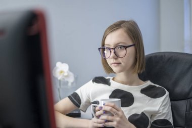 Üniversitede ya da üniversitede uzaktan öğrenim gören bir kız öğrenci. Uzaktan bilim. Evde internet öğretmenine webinar öğretiyor. özet ya da not defterine notlar. Karantina sırasında çay içer.