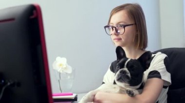 Öğrenci kız. Mesafe öğrenme. Bilgisayarda ya da dizüstü bilgisayardaki notları dinleyen bilim ya da dersler. Evde kalmak. Bir salgın sırasında karantinaya alınan komik bir köpek ya da evcil hayvan ile..