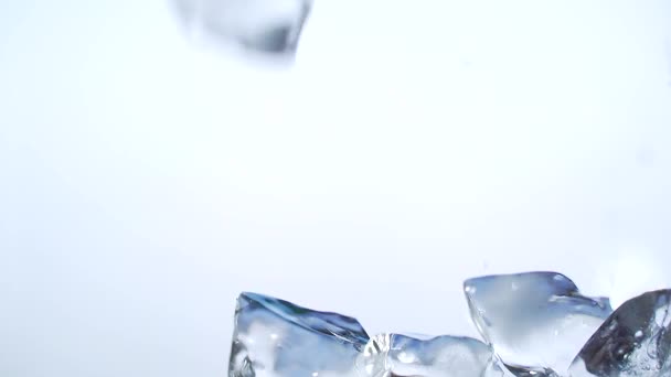 白い背景のガラスから氷の立方体が落下します 閉めろ スローモーション 接近中だ マクロだ 氷がガラス容器を満たしています 氷の部分が違う 抽象的 冷たい飲み物を作ることで — ストック動画