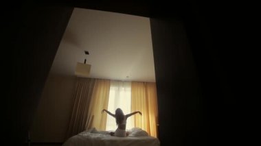 Bir kızın silüeti. Pencerenin arka planında gerilmiş. Sabah kalktığında yatak odasında ya da otelde. Daire. Beyaz yatak, iç çamaşırı. Çekici kadın dikiz aynası. Sıcak, güneşli.