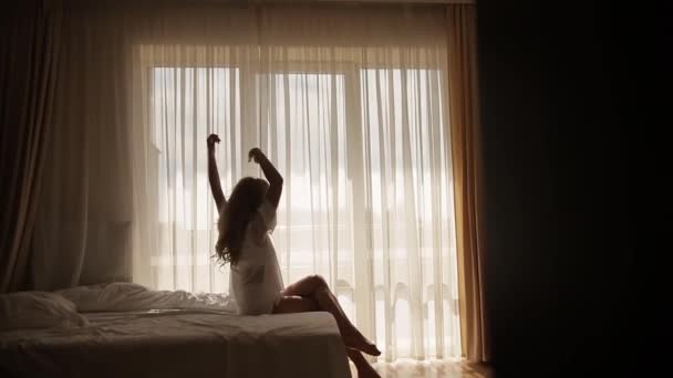 魅力的な女の子のシルエット ベッドルームで朝起きて足を伸ばしてた 太陽が輝いている 朝の太陽が居心地の良い部屋を通して輝いている フィットネス フレッシュ ウーマン — ストック動画