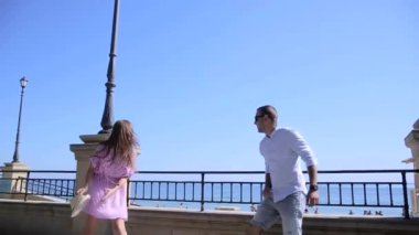Genç renkli bir çift, hippiler, renkli iki kişi, deniz kenarında eğleniyorlar, yaz, güneşli hava, pembe ışıkta eğlence ve eğlence, beyaz gömlek, kot şort şapka, balayı