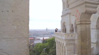 Gelinler eski bir kalenin balkonunda ya da terasında birbirlerine sarılıp öpüşürler. Eski şehir manzarasının arka planında. Nehir manzaralı. Ağır çekim. Budapeşte. Buda Avrupa Boşluk metnini kopyala