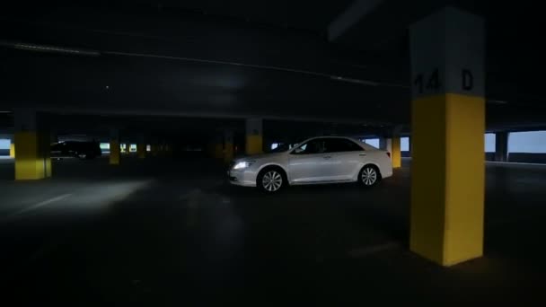 白色的车 轿车在黑暗的地下停车场开着灯 覆盖停车 慢动作 很棒的别致的车豪华轿车 购物中心 — 图库视频影像