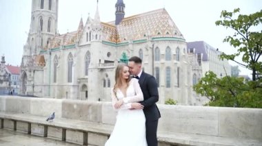 Genç düğün çifti portresi, eski şehir geçmişi, tarihi şato ve mimari, açık havada gelin damada sarılıyor birbirine yaslanıyor, öpüşüyor, okşuyor, lüks düğün faşisti.