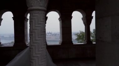 Genç ve çekici bir moda kızının silueti, kadın. Sütunları ve pencerenin arka planındaki kemerleri geçip şehre, eski binaya ve mimariye bakıyor. Kadın. lüks. 