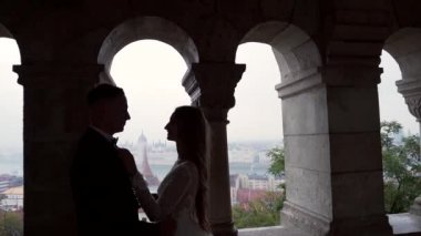 Kendine güvenen damat ilk kez mutlu bir gelinle tanışır, onu gelinlik içinde, pencerenin kenarında bir siluet görür. Evli çift, eski Castle City arka planındaki kemer ve sütunların yanında sarılıp öpüşüyor.