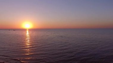 Güneşin doğuşu ya da batışı, denizin arka planında, balıkçı teknelerinin deniz dalgaları, güneş suya yansıyor. Sakin okyanusun ufuktaki yaz manzarası. Kum. Hava manzaralı. Rahatlama ve meditasyon