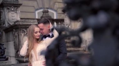 Genç bir çift portresi. Uzun sarı saçlı bir erkek ve kız. Kadim kale mimarisinin arka planına karşı, eski kasaba. Kare, sütunlar, balyalar, merdivenler ve taş binalar. Gelin damat