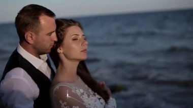 Yakın plan, büyüleyici genç bir çiftin portresi. Gelinlik içinde. Lüks lüks, ciddi gelin ve damat, iki yüzlü. Adam saça dokunuyor. Omzundan öpücükler. Romantik gözler