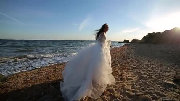 Uzun Saçlı Beyaz Gelinlikli Çekici Bir Kız Deniz Kıyısında Yürüyor — Stok video