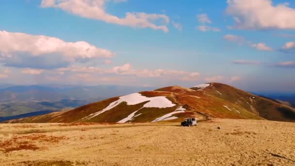 Suvは山の上を運転しているか立っている 山の尾根に沿って極端な旅 青と金の山々の風景は 雪の中でピーク 野生の自然オフロードジープ — ストック動画