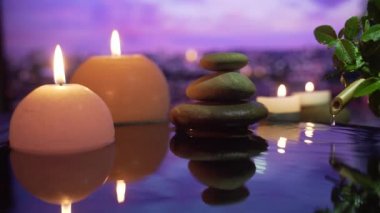  Spa Still Life, Stones masajı ve Su Rahatlaması. Kapatın. Yanan mumların rahatlatıcı görüntüsü. Bulanık arka planda su yansıması. Rahatlama, meditasyon, huzur ve sessizlik..