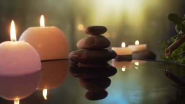 Suda yanan mumlar, akşam doğasında taşların yansıması, düşen su damlaları. Ağır çekim. Yakın çekim kavramı: rahatlama, sağlık, vücut bakımı, spa, aromaterapi