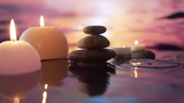 Suda yanan mumlar, akşam doğasında taşların yansıması, düşen su damlaları. Ağır çekim. Yakın çekim kavramı: rahatlama, sağlık, vücut bakımı, spa, aromaterapi
