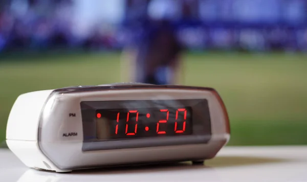 White electronic clock with a red dial. White clock with an alarm clock