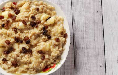 Elma ve üzüm eski ağaç arka planı yulaf ezmesi. Bir elma ve kuru üzüm ile müsli